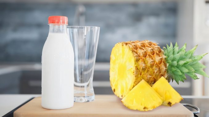 pineapple juice in clear drinking glass beside pineapple fruit